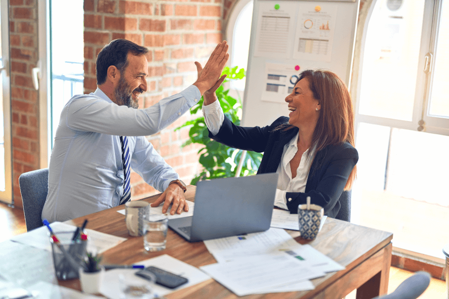 Stock photo of man and woman in business attire giving a high five.