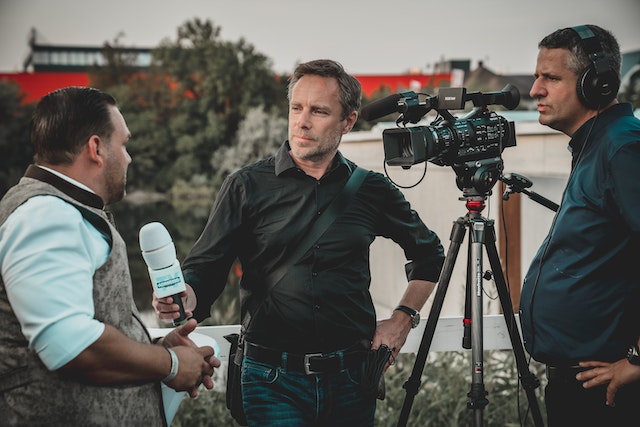 Man Holding Microphone While Talking to Another Man In Front Of Camera